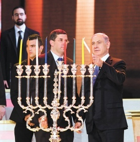 The Chanukiah 1 Prime Minister Netanyahu of Israel lighting a chanukiiah on 8th night Chanukah. He uses the shamash light (which, in this chanukiah, will be placed in the central location and higher than the other lights to distinguish it from them) to ignite all the other lights.